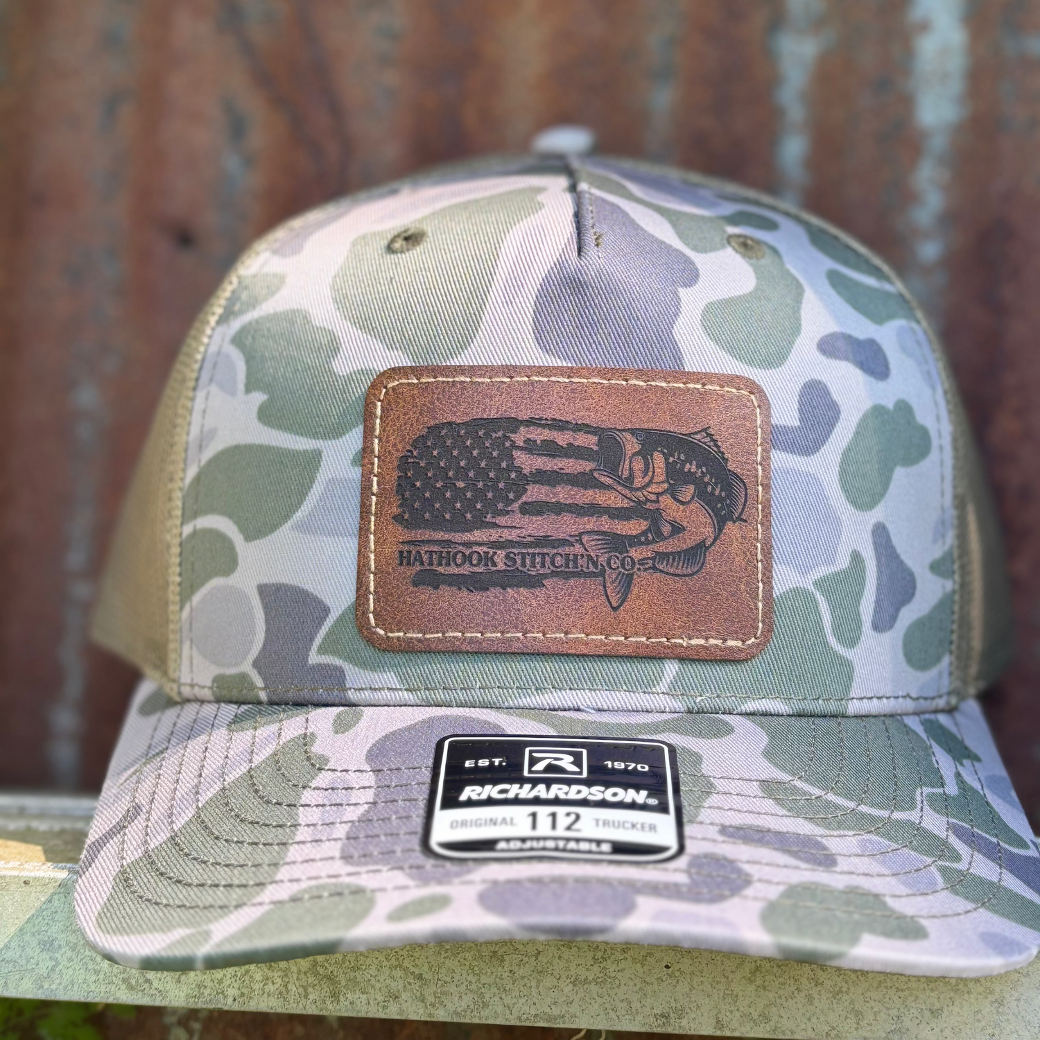 Camouflage baseball cap with leather patch and Richardson logo on a wooden surface
