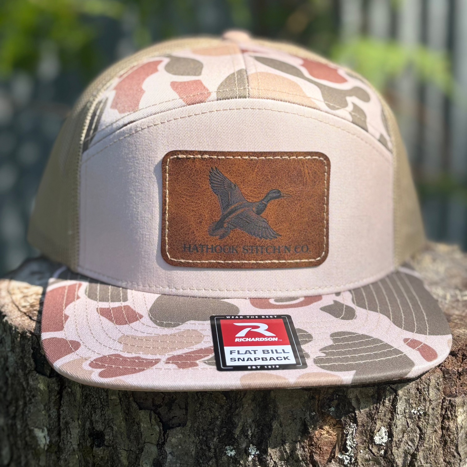 Camouflage-patterned cap with leather patch on a tree stump
